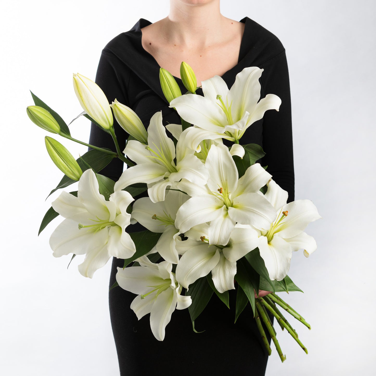 Woman wearing a black dress, holding a bouquet of white lilies