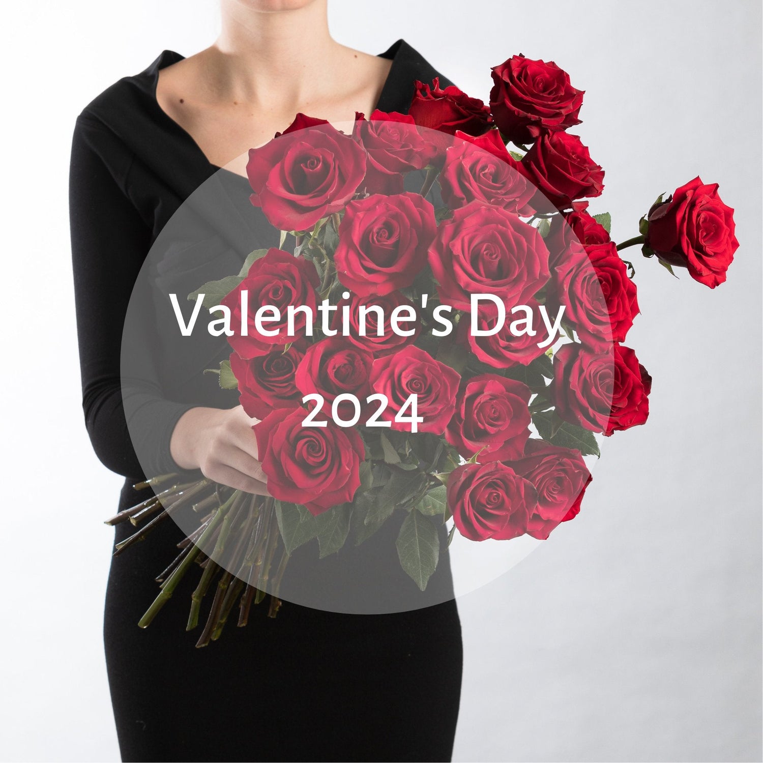 A woman wearing black holding a bunch of long stemmed red roses made in a bouquet.