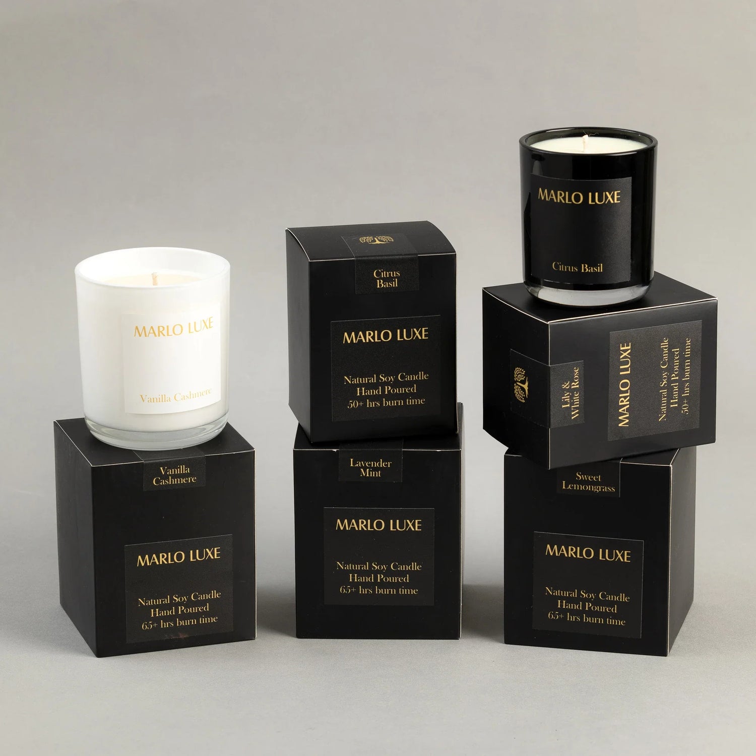 A selection of candles in white glass and packaged in a black bow with gold font.