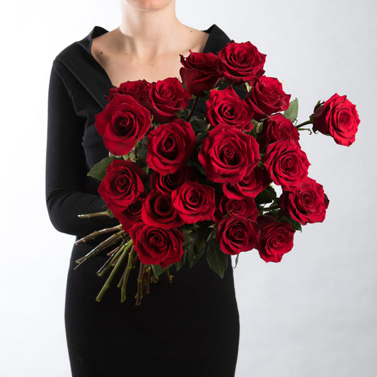 Woman wearing a black dress, holding a bouquet of premium red roses.