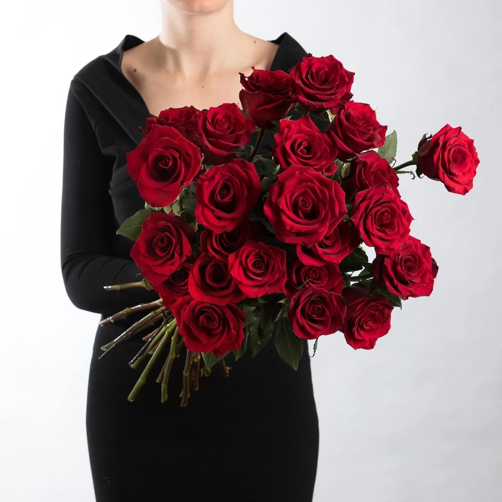 A bouquet of roses arranged in a classic, elegant style with lush green leaves and long stems for a timeless, romantic look.